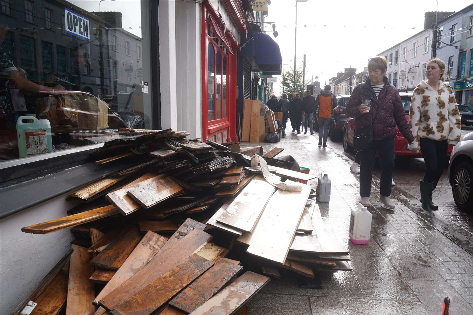 People walk past damaged shops on Main Street in Midleton, Co Cork, after Storm Babet swept in Brian Lawless/PA)
