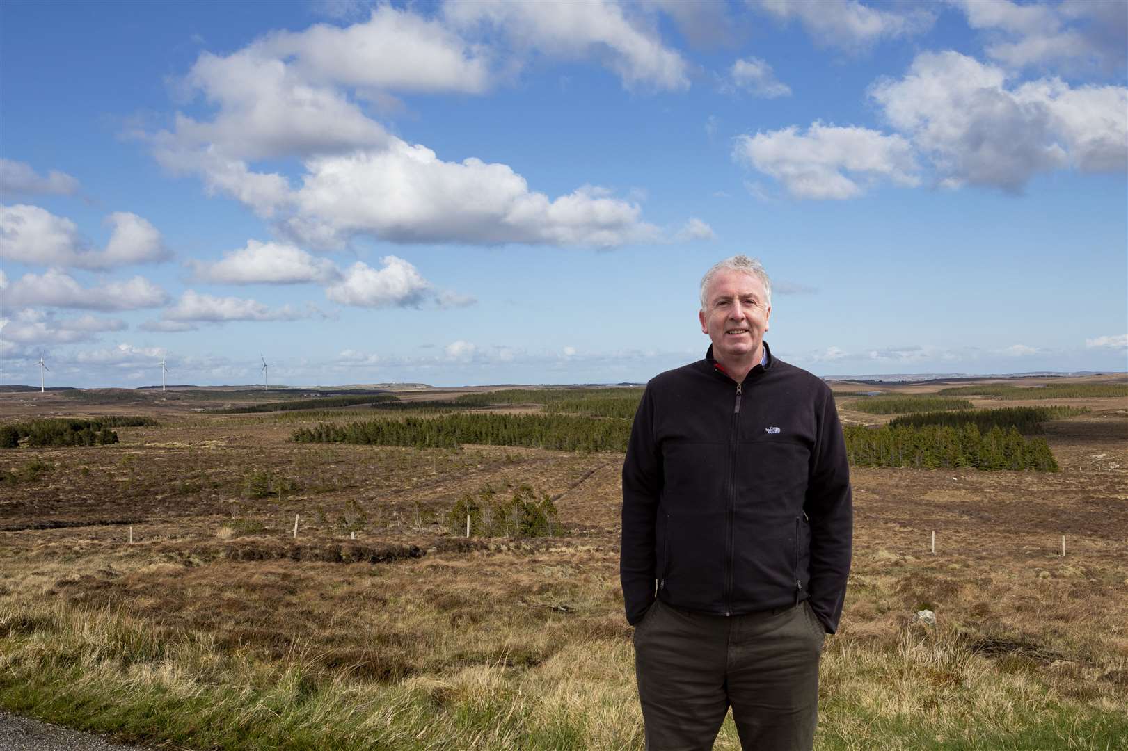 Calum MacDonald, with Point and Sandwick Trust’s Beinn Ghrideag turbines in the background.