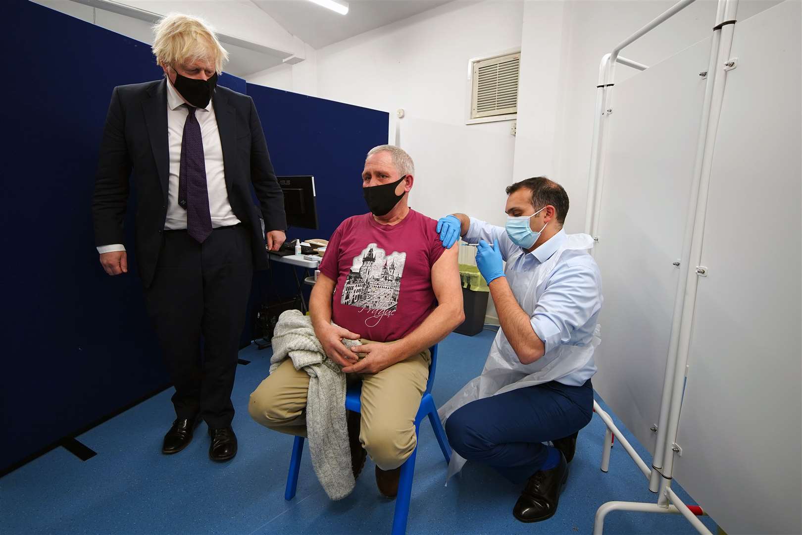 Prime Minister Boris Johnson watches someone receive their Covid-19 booster vaccine (Peter Byrne/PA)
