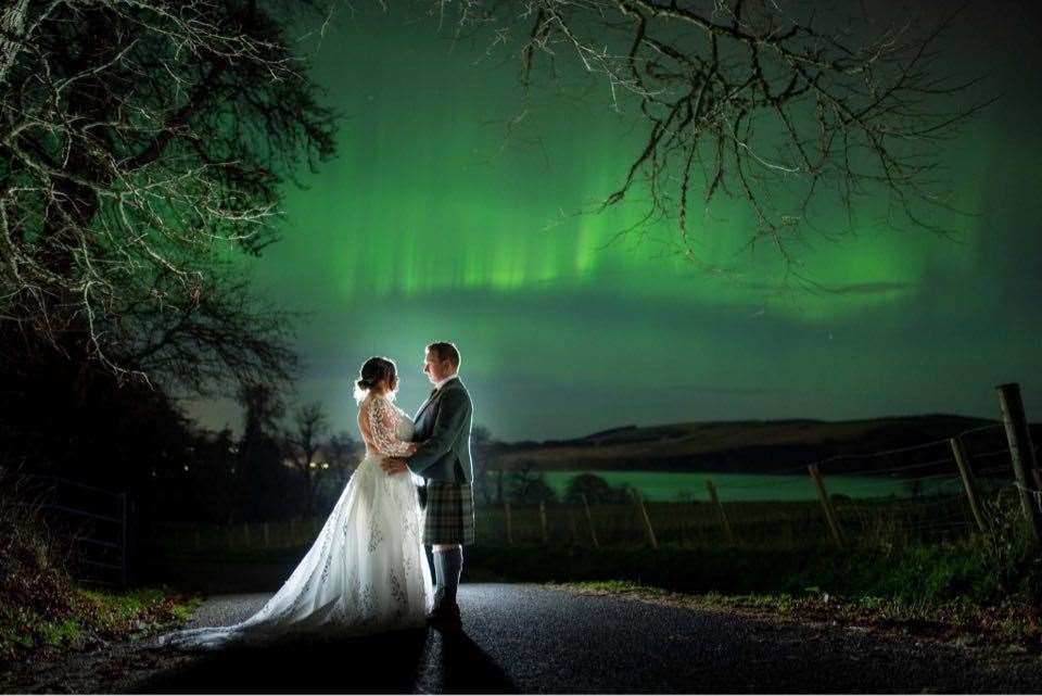 Inverness newly weds illuminated in spectacular Northern Lights picture.
