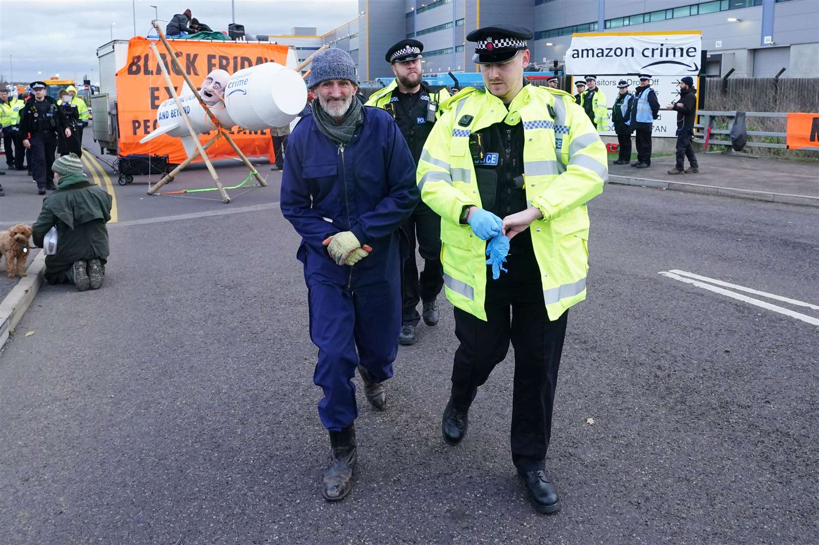An activist from Extinction Rebellion is led away by police as they block the entrance to the Amazon fulfilment centre in Tilbury, Essex (Ian West/PA)