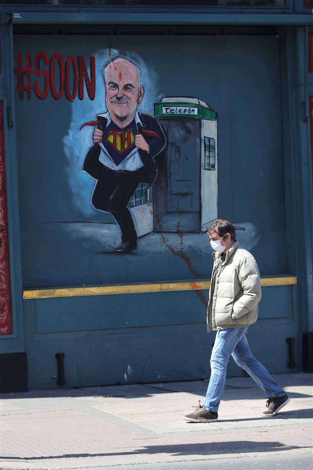 A man walks past a mural depicting Dr Holohan, outside Davitts Pub on Camden Street, Dublin (Niall Carson/PA)
