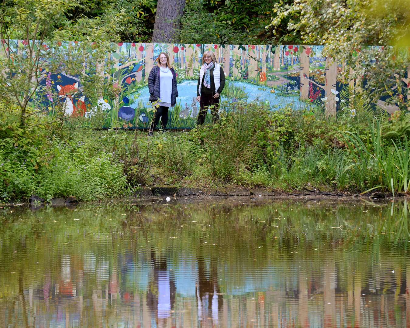 Artists Heather Afrin (left )and Susan McCreevy with a view of the mural beside the duck pond. Picture: Gary Anthony