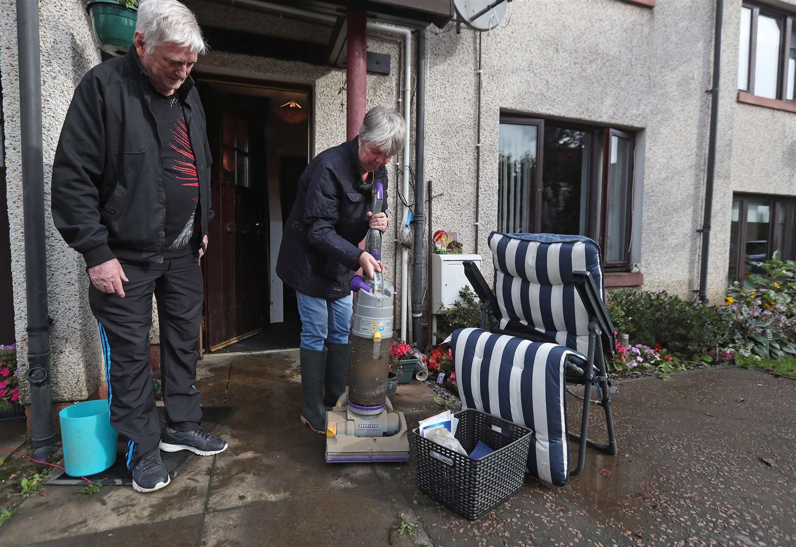 Jean Hendrie and William Craik cleaning their house in Pyothall Court in Broxburn after flooding (Andrew Milligan/PA)