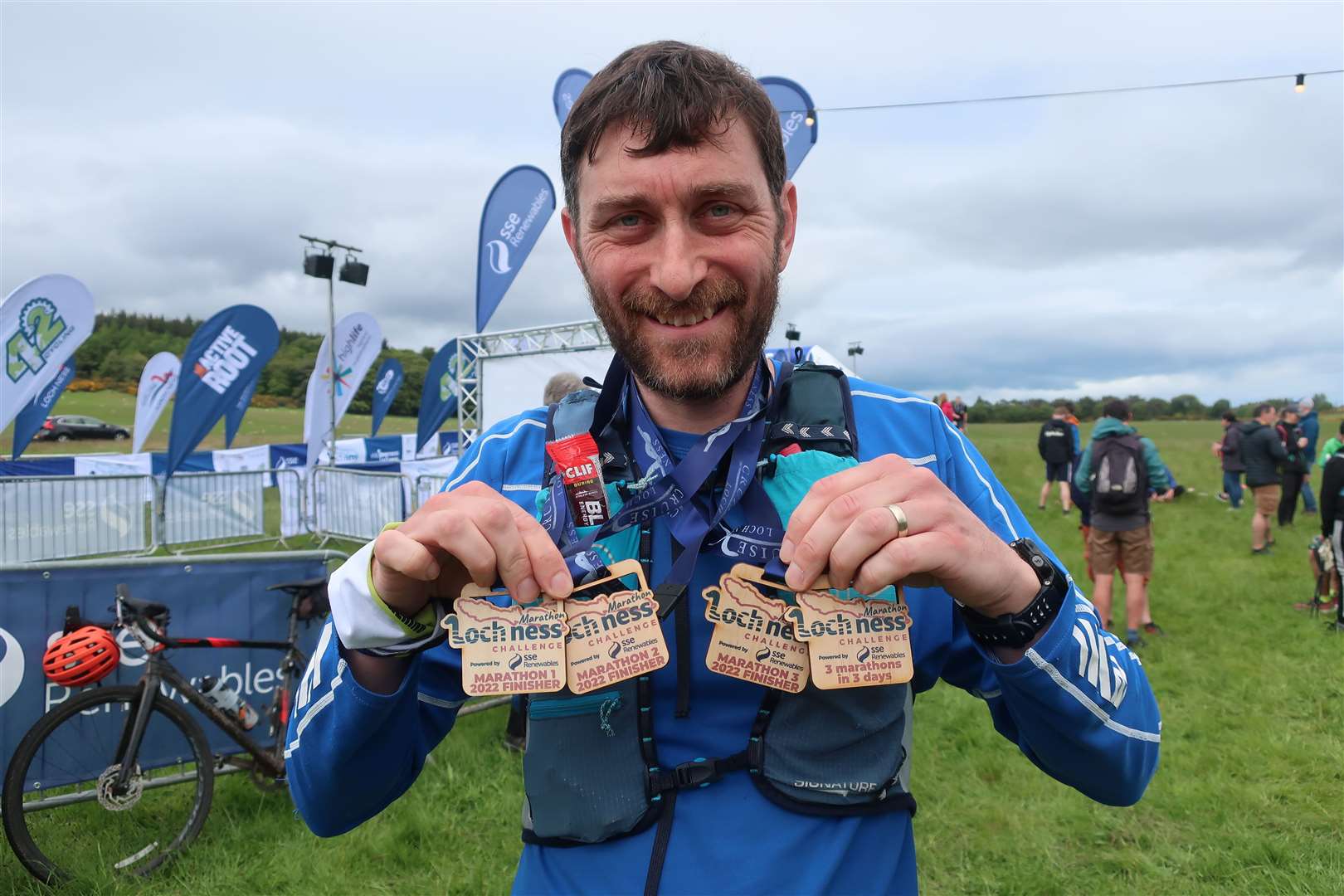 John holds his four medals - one for each marathon and one for completing all three - at the even hub in Dores.