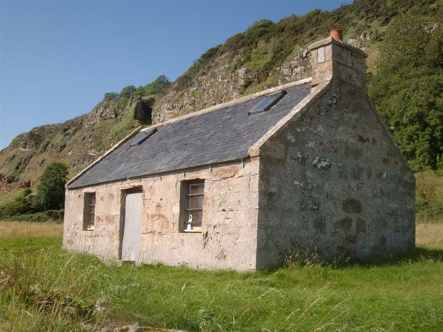 The renovated fishing bothy reached after a gap in a drystone wall.