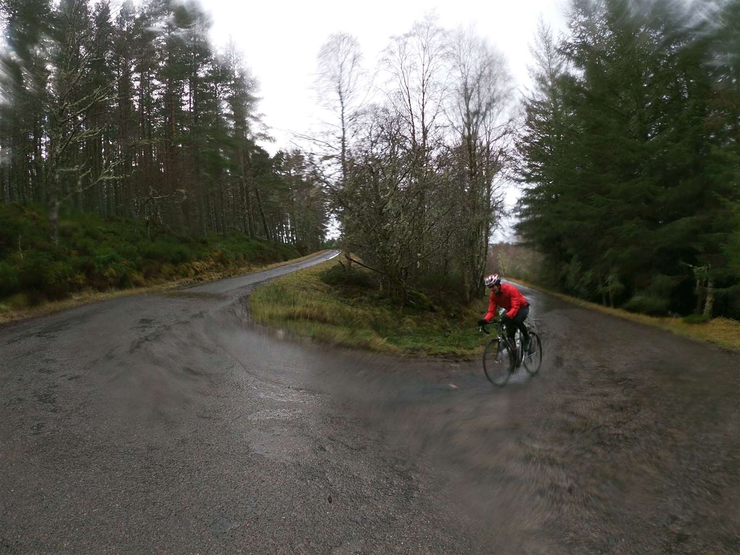 A cyclist negotiates the wet conditions on a hairpin bend near the top of McBain.