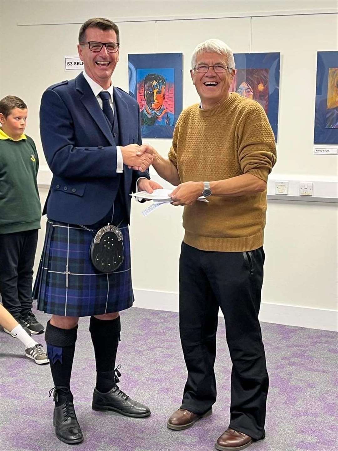 Pipe Major Kevin Reid of Nairn and District Pipe Band receiving the donation from Donald Wilson of the Nairn Ceilidh Group.
