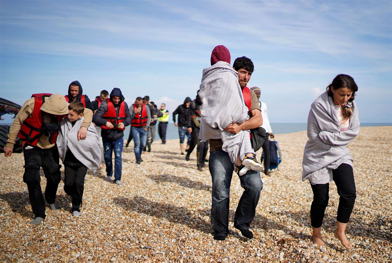 A group of people thought to be migrants walk ashore in Dungeness, Kent, after being intercepted by the RNLI in a small boat incident in the Channel (Gareth Fuller/PA)
