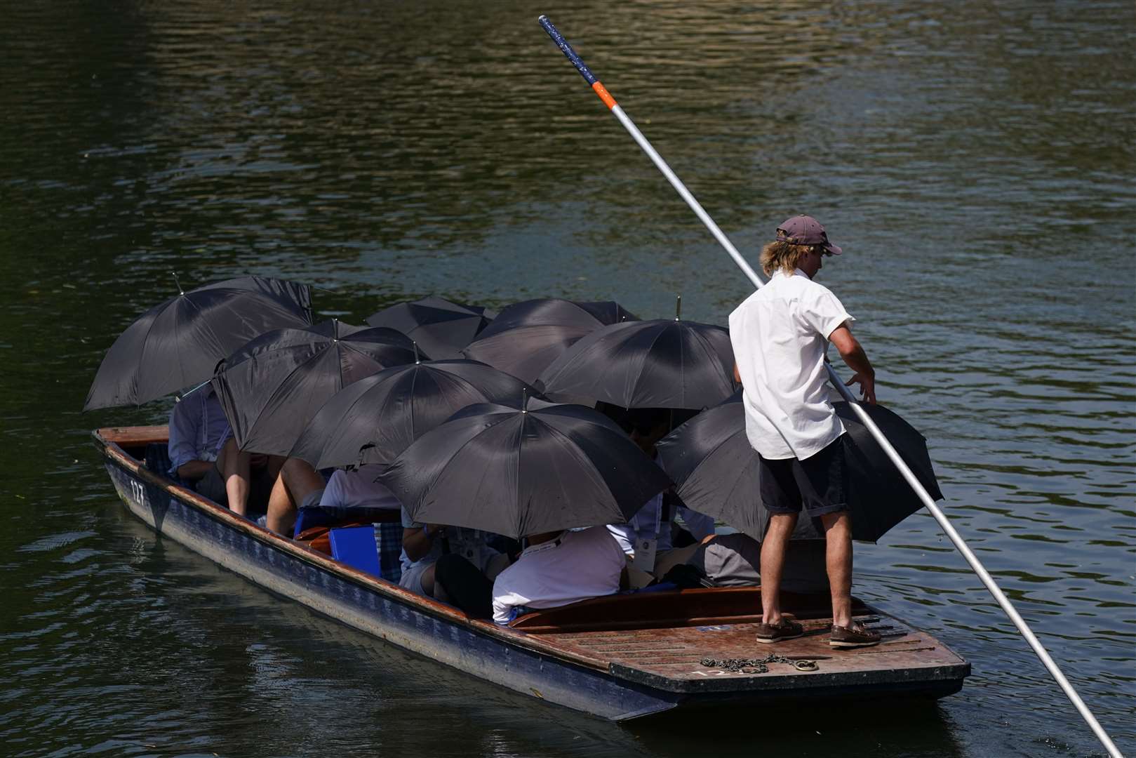 People under umbrellas being punted along the River Cam in Cambridge (Jacob King/PA)