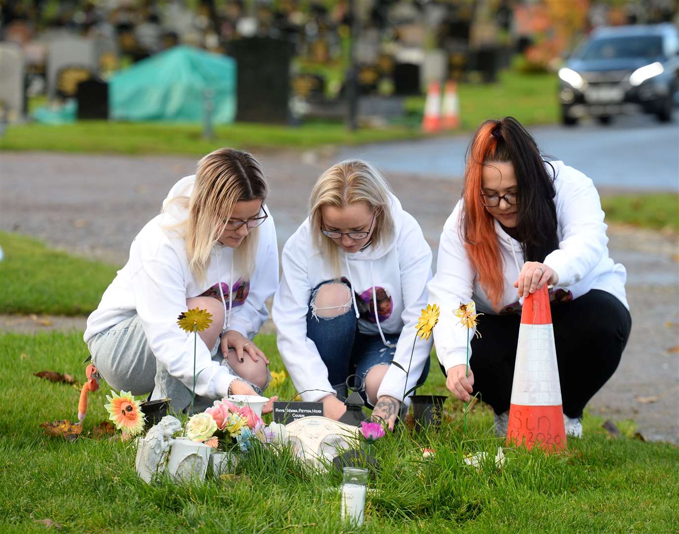 Beside the grave of family are Rhys's sisters Vikki Fyall (left) and Jamielee Cousin with lifelong friend Donna Bain.