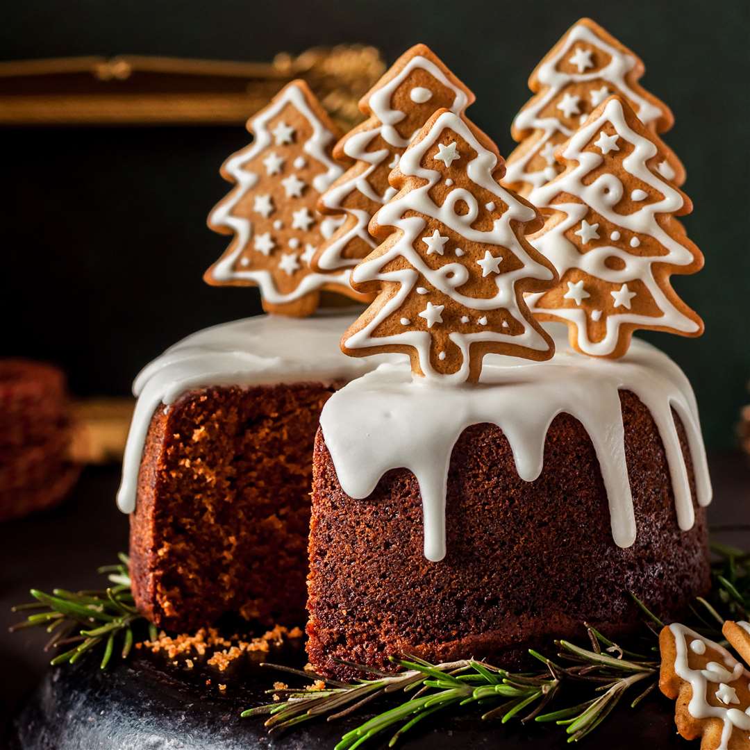 Sliced gingerbread cake decorated with spiced Christmas cookies.