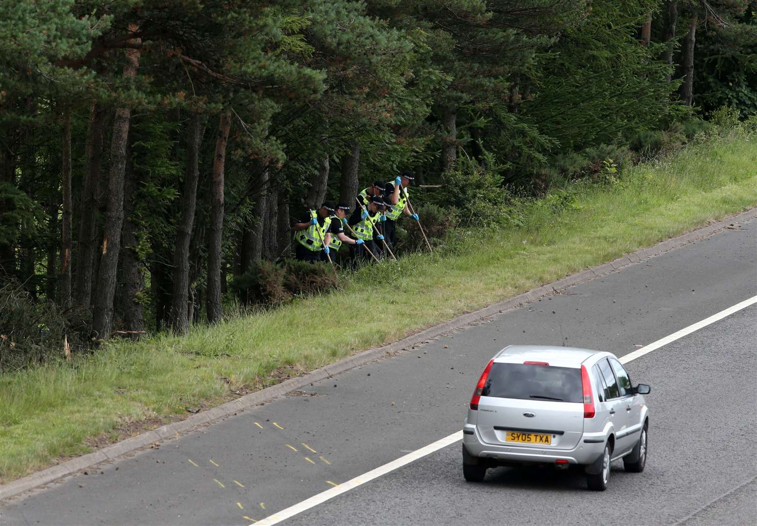 Police officers search the scene of the crash at junction nine of the M9 (Andrew Milligan/PA)
