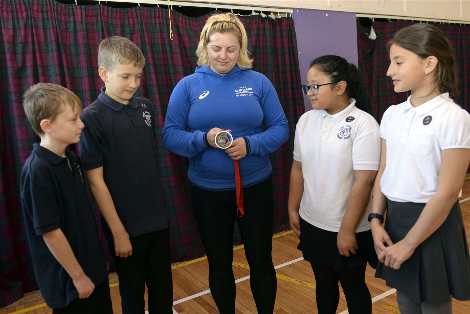 Steph Inglis shows her silver Commonwealth Games medal to young students.