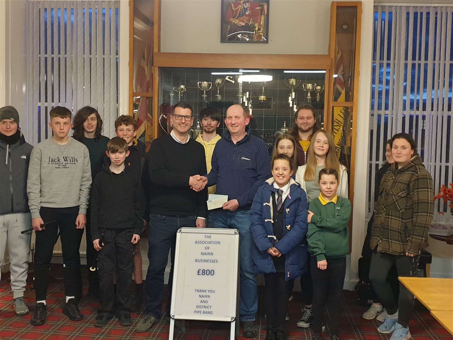 Nairn & District Pipe Band's pipe major Kevin Reid receiving the donation cheque from Gordon Chisholm, chairman of the Nairn Business Association.