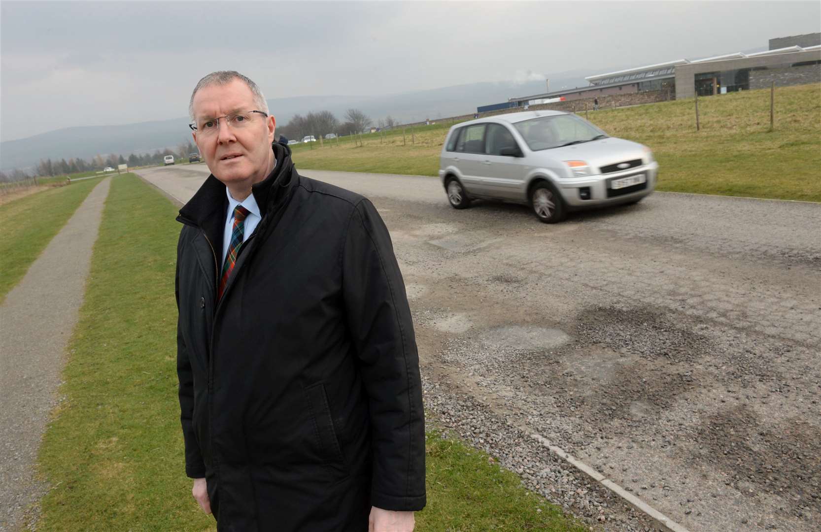 Councillor Duncan Macpherson at potholes on the road into Culloden Battlefield.