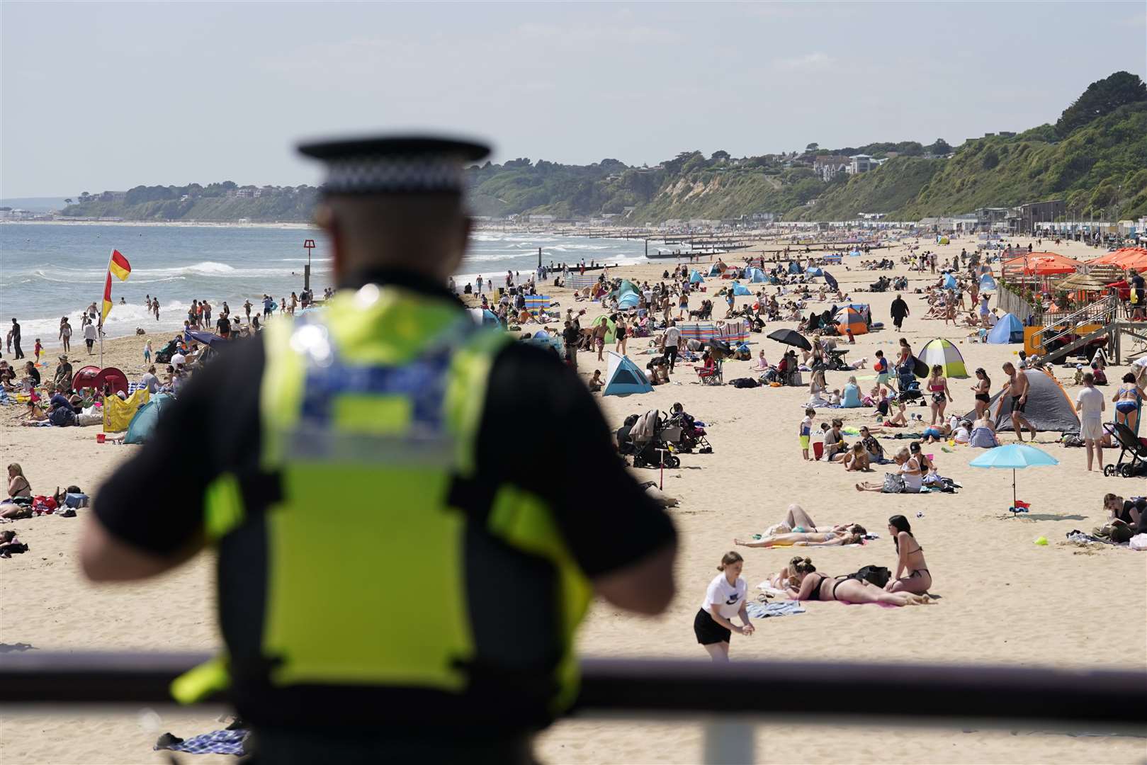 A police officer looks out over Bournemouth beach after a 17-year-old-boy and 12-year-old girl drowned (PA)