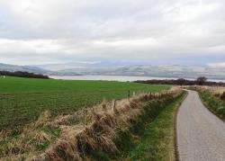 Looking down the minor road beside the A9 overlooking Ben Wyvis (in cloud) and Dingwall across the Cromarty Firth.