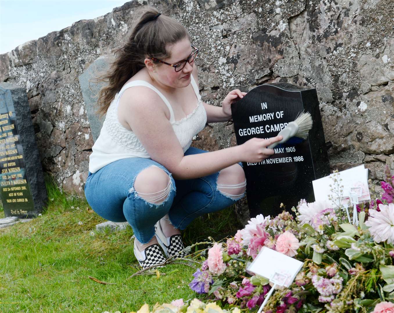 Kelcy Campbell wipes down a headstone. Picture: Gary Anthony