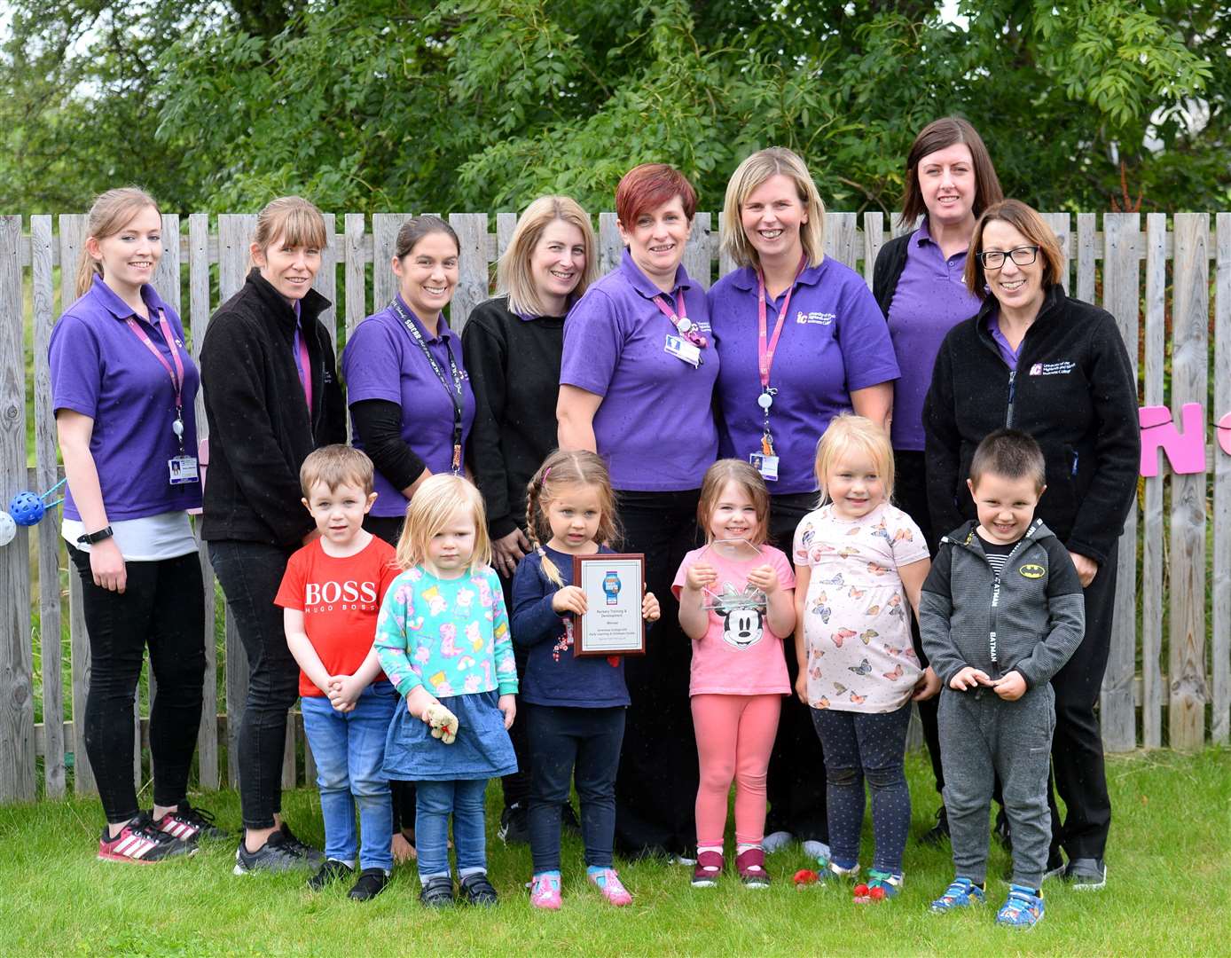 Staff, including centre manager Cat Mackenzie (back, third right) and children with award and plaque.