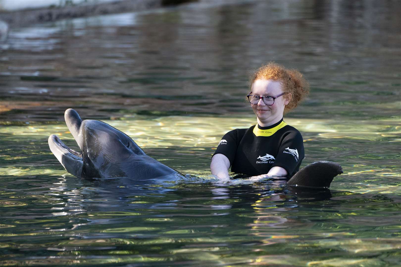 Emma Huey, 14, from Ballymoney in Co Antrim, swims with a dolphin during the Dreamflight visit to Discovery Cove in Orlando, Florida (Kirsty O’Connor/PA)