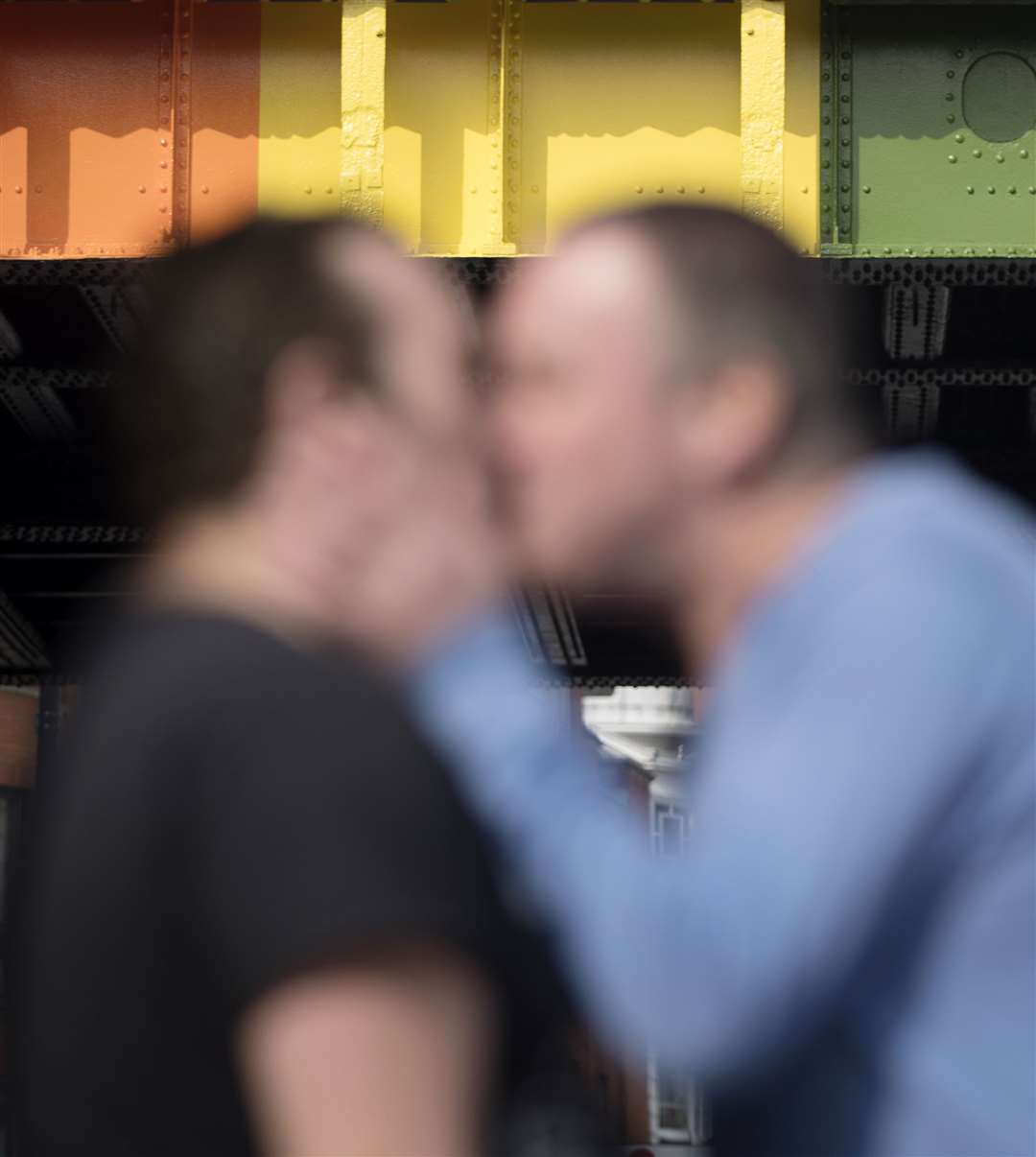 Two men kiss in front of a rainbow coloured bridge in Leeds (Danny Lawson/PA)