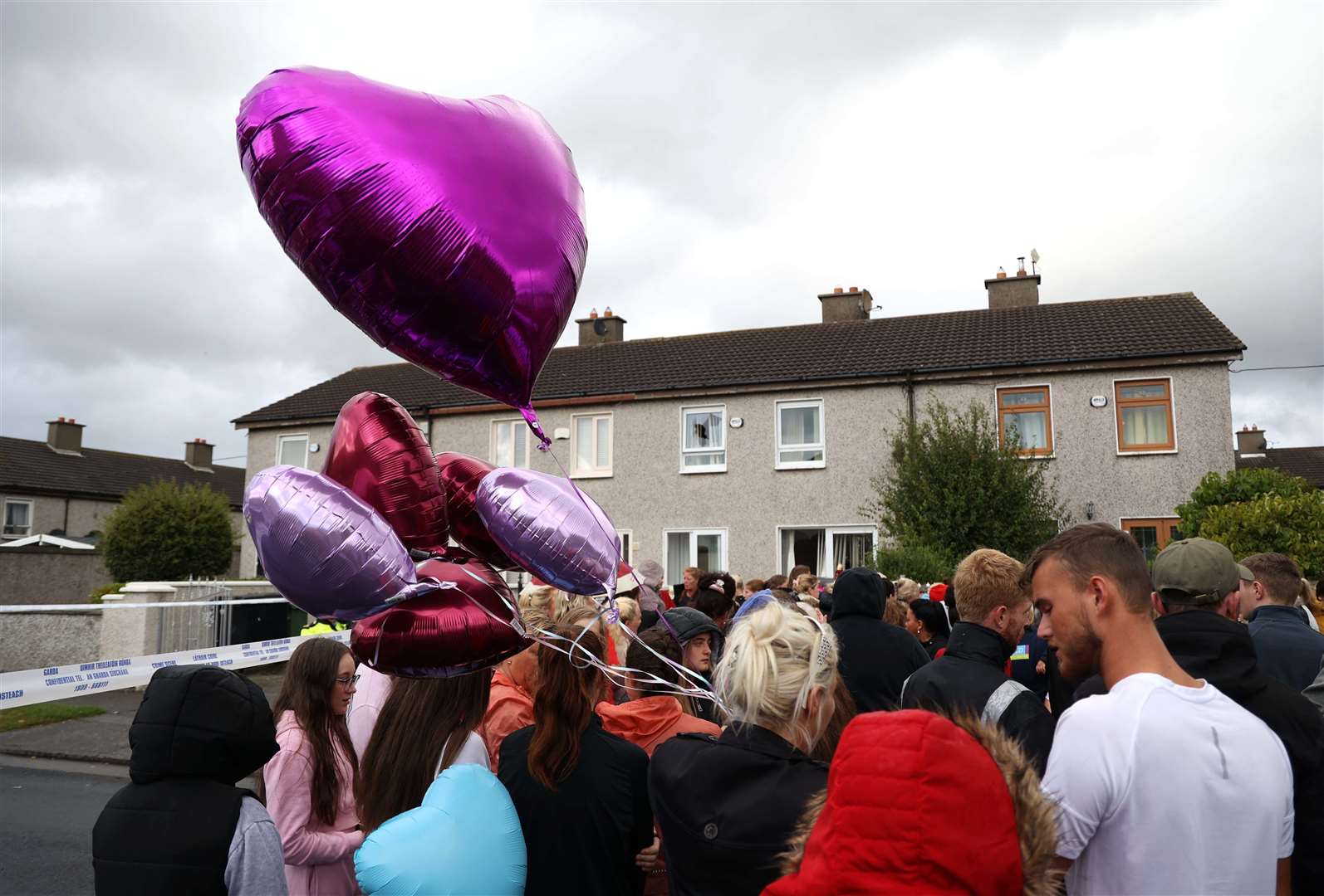 People attend a vigil outside a house on Rossfield Avenue in Tallaght, Dublin, where Lisa Cash, 18, and her eight-year-old twin siblings Christy and Chelsea Cawley died (Damien Eagers/PA).