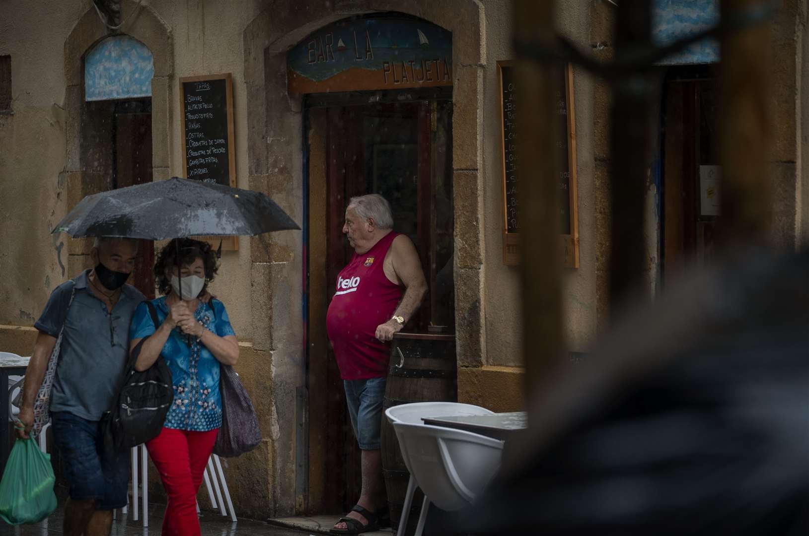 A man stands in a bar entrance as people walk by in Barcelona, Spain (Emilio Morenatti/AP)
