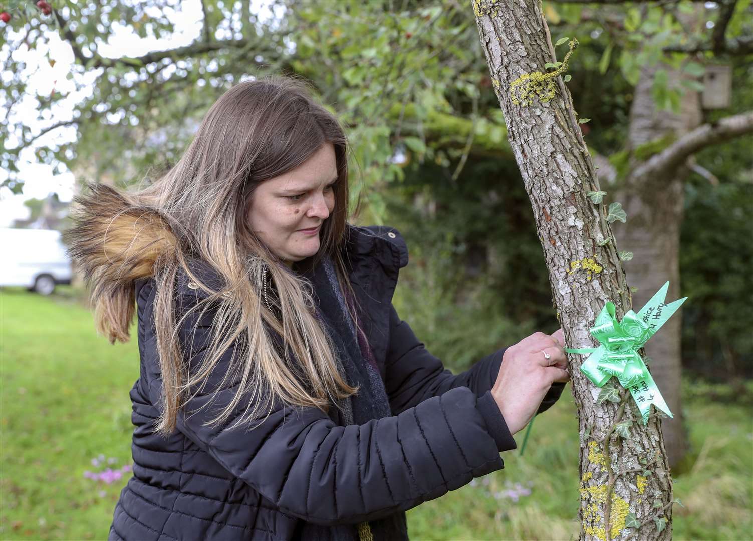 Harry Dunn’s aunt, Katie Grant, ties green ribbons around a tree in his memory (Steve Parsons/PA)