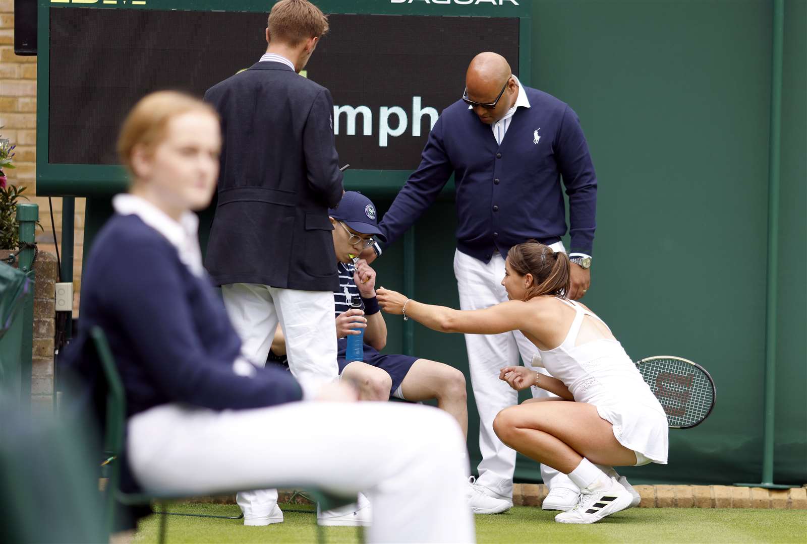 Jodie Burrage helps a ball boy during her match against Lesia Tsurenko (Steven Paston/PA).