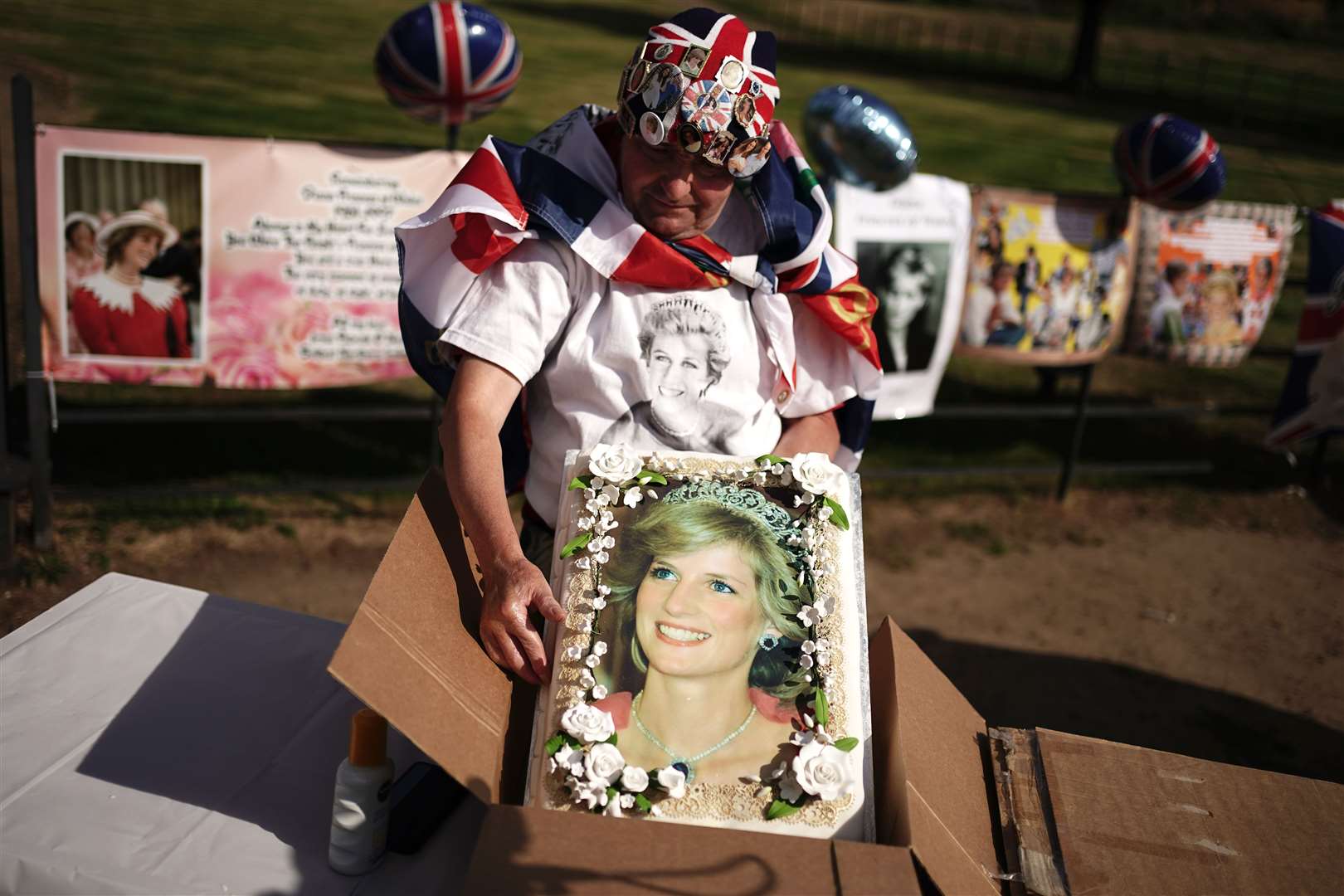 Royal fan John Loughrey opens a box containing a large cake with an image of Diana, Princess of Wales, outside her former home Kensington Palace (Aaron Chown/PA)