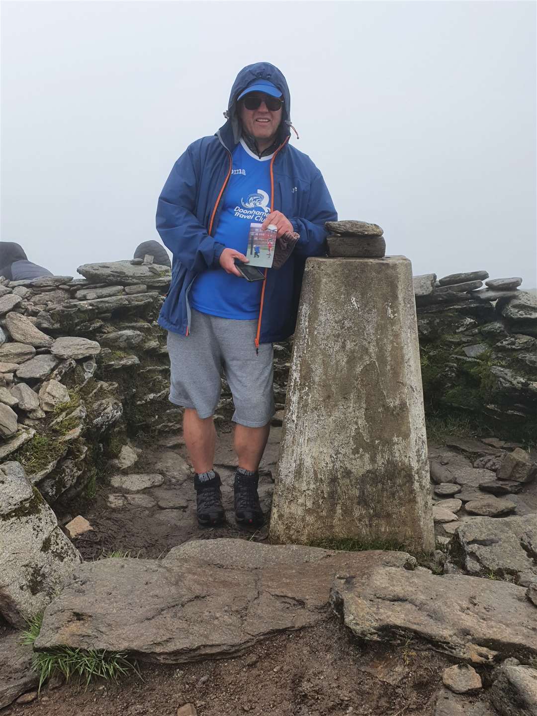 Chris with the photo of his dad and the Queen of the South football shirt at the summit trig point.