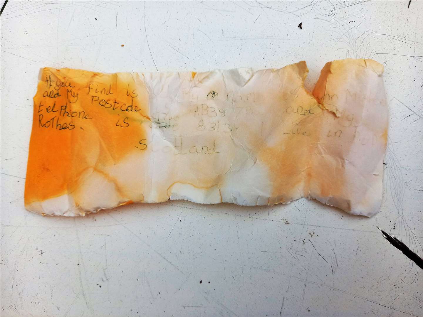 The orange scrap of paper the message was written on has become faded over the years.