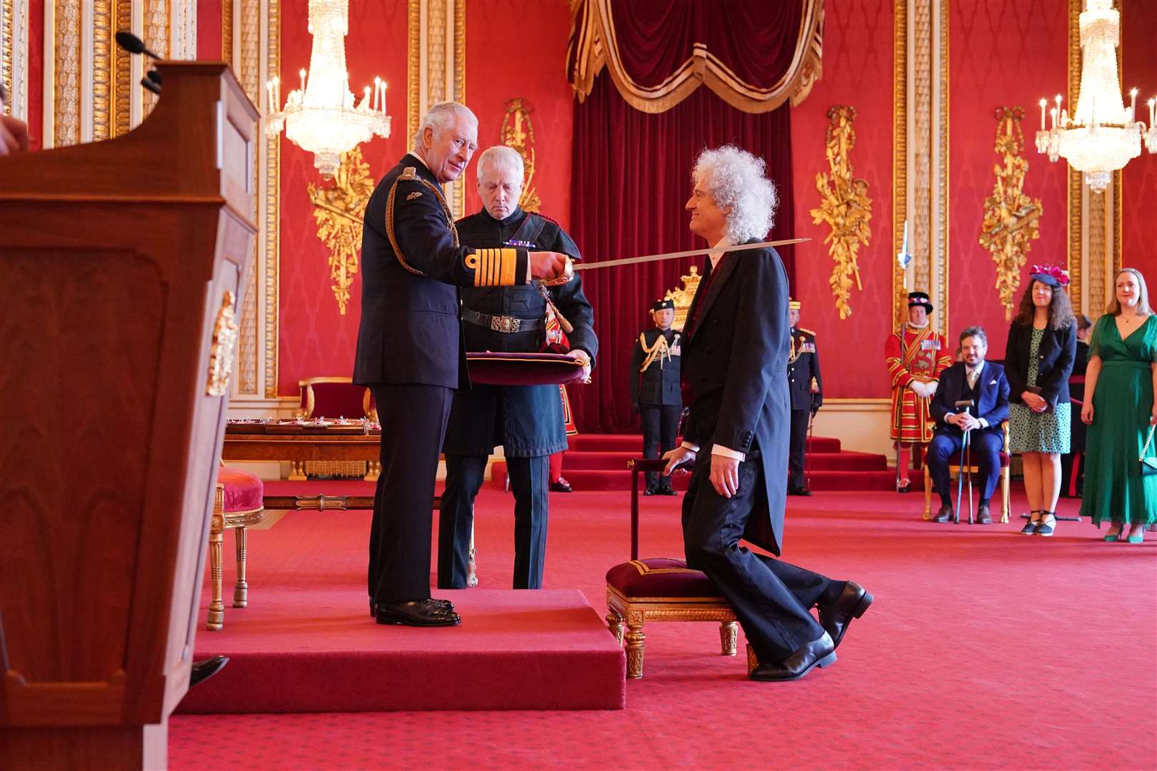 The King confers a knighthood upon the Queen guitarist (Jonathan Brady/PA)