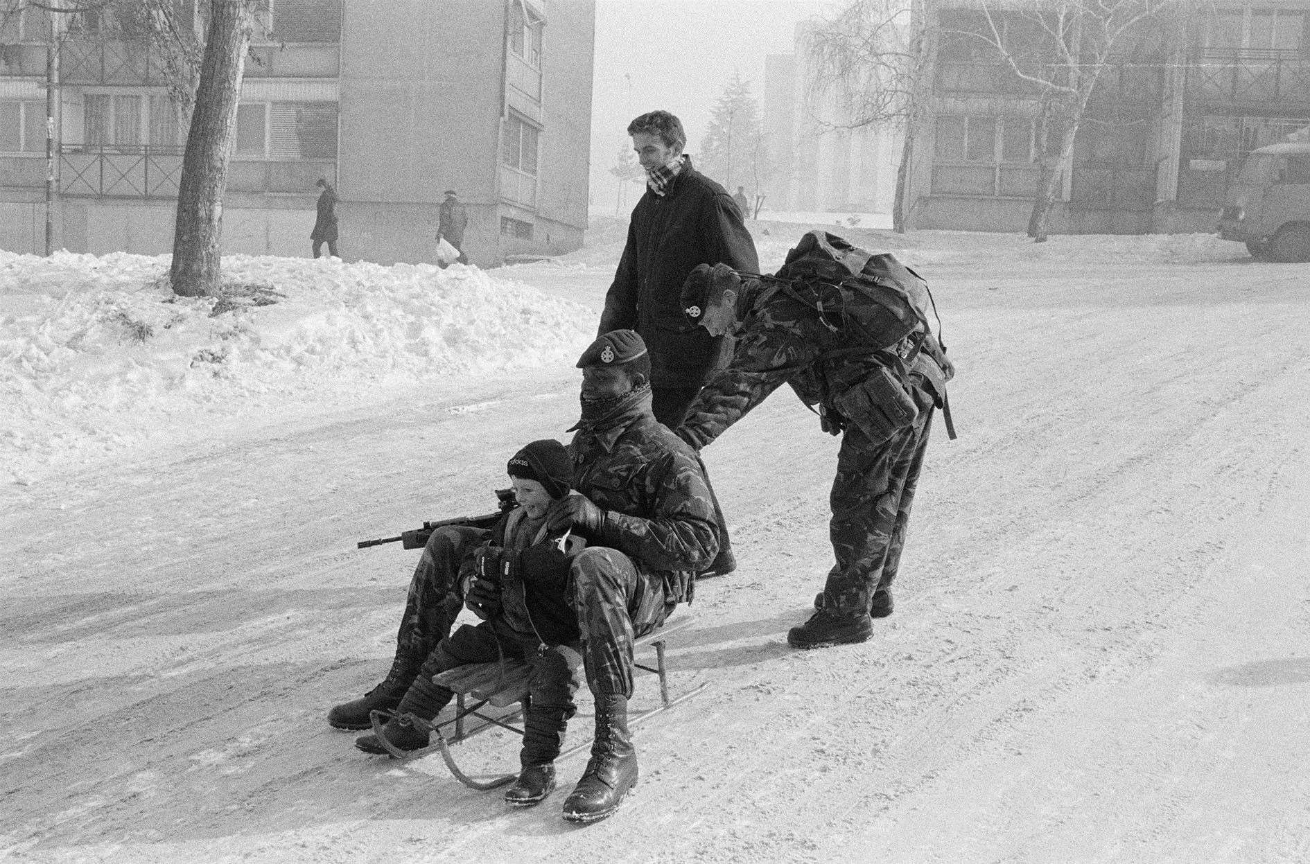 Kosovo image – soldier with boy on sled in snow. Picture: Nick Sidle