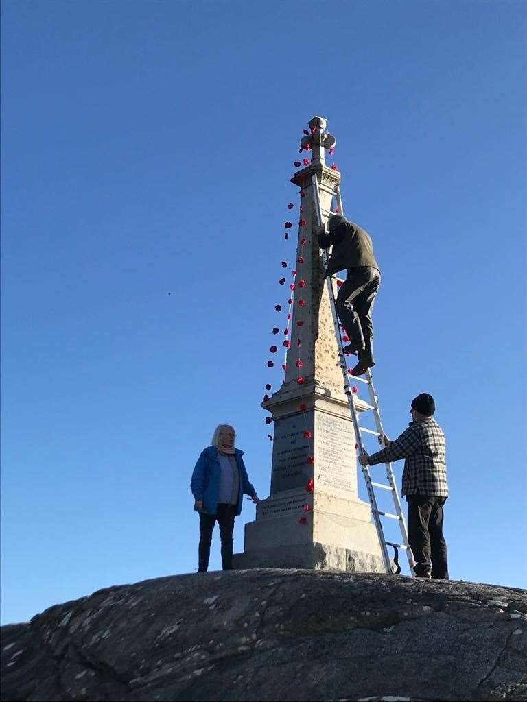 A precarious task, fixing the poppy netting to the memorial