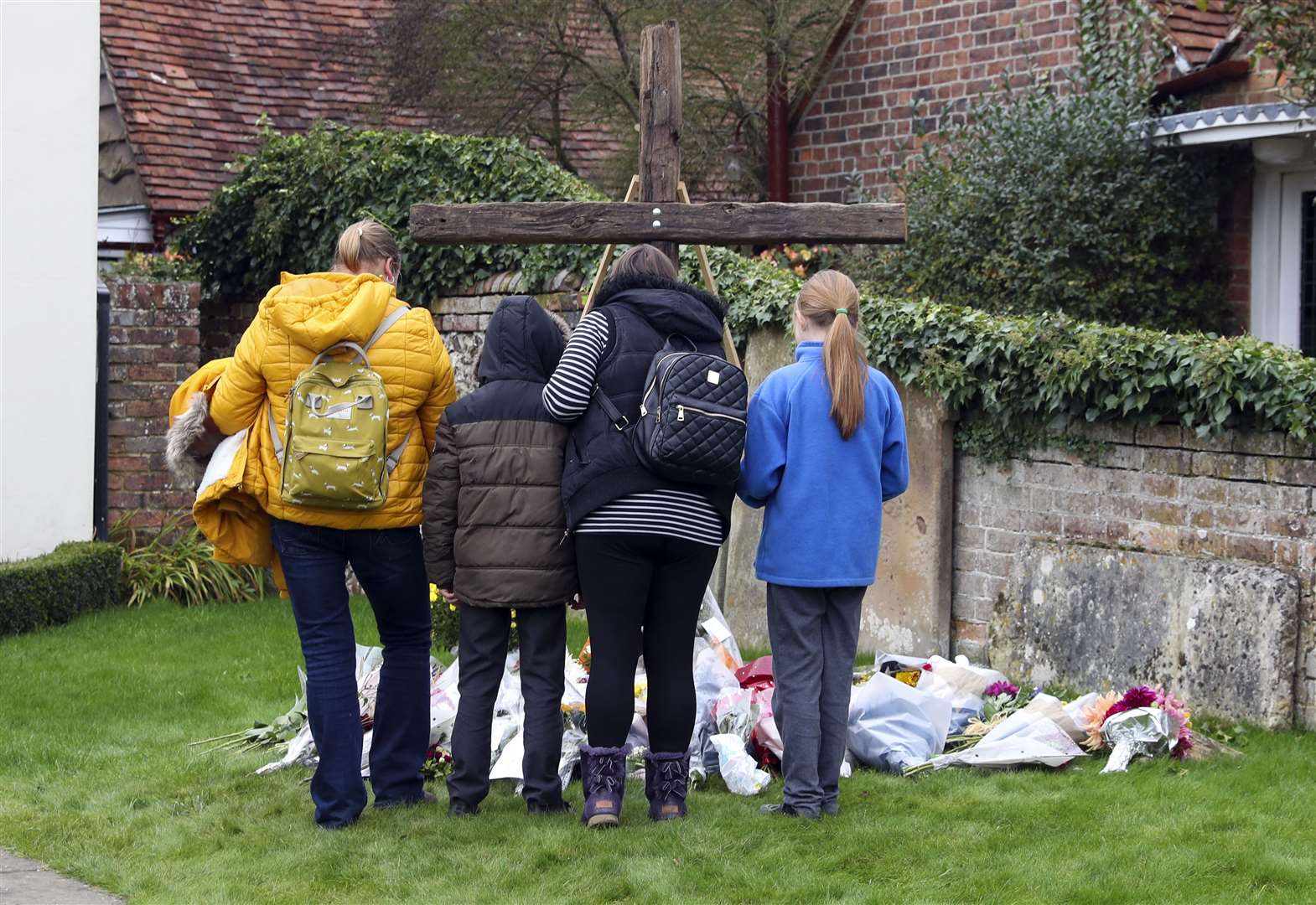 People pay their respects next to floral tributes left outside Chinnor Community Church in Oxfordshire, in memory of Zoe Powell, 29, and her three children (Steve Parsons/PA)