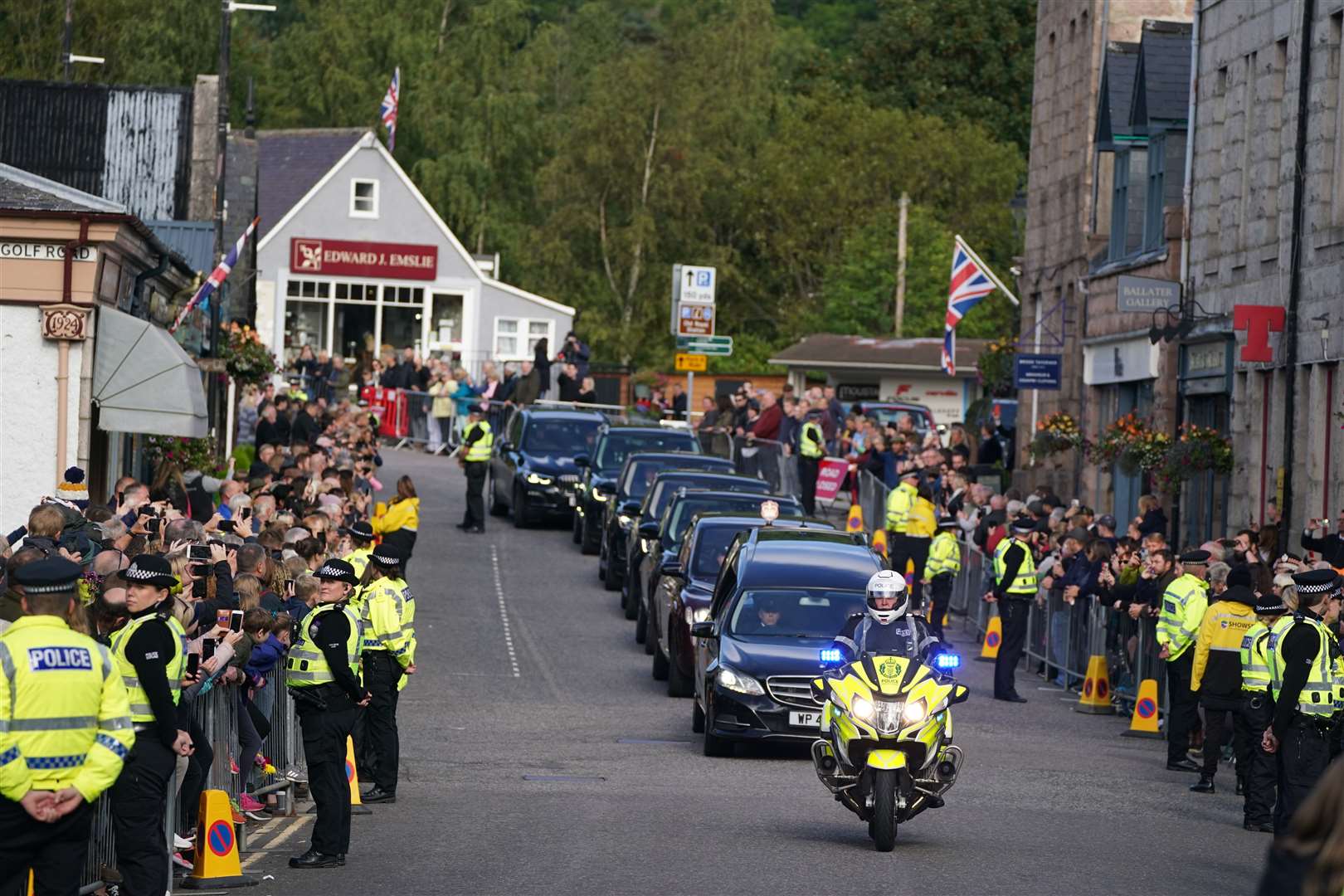 The hearse carrying the coffin of Queen Elizabeth II, draped with the Royal Standard of Scotland, passing through Ballater as it continues its journey to Edinburgh from Balmoral (Andrew Milligan/PA)