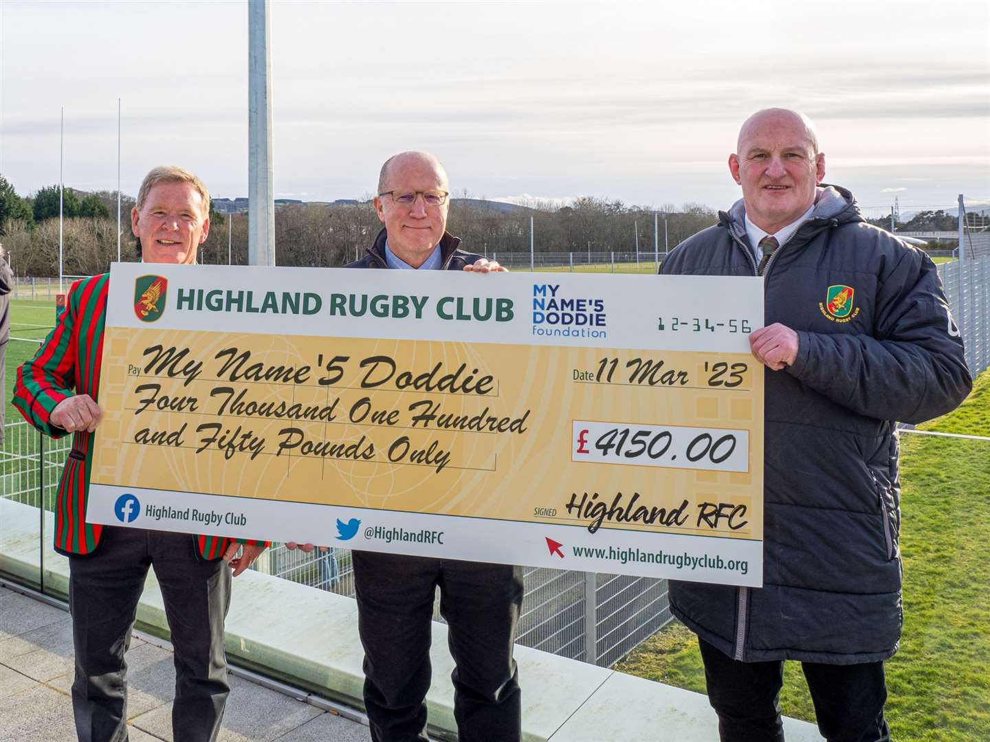 Roy Dinnes (President Highland RFC), Andy Kent (representing My Name’5 Doddie), and Graham Findlater (Highland RFC) with the cheque for My Name'5 Doddie.