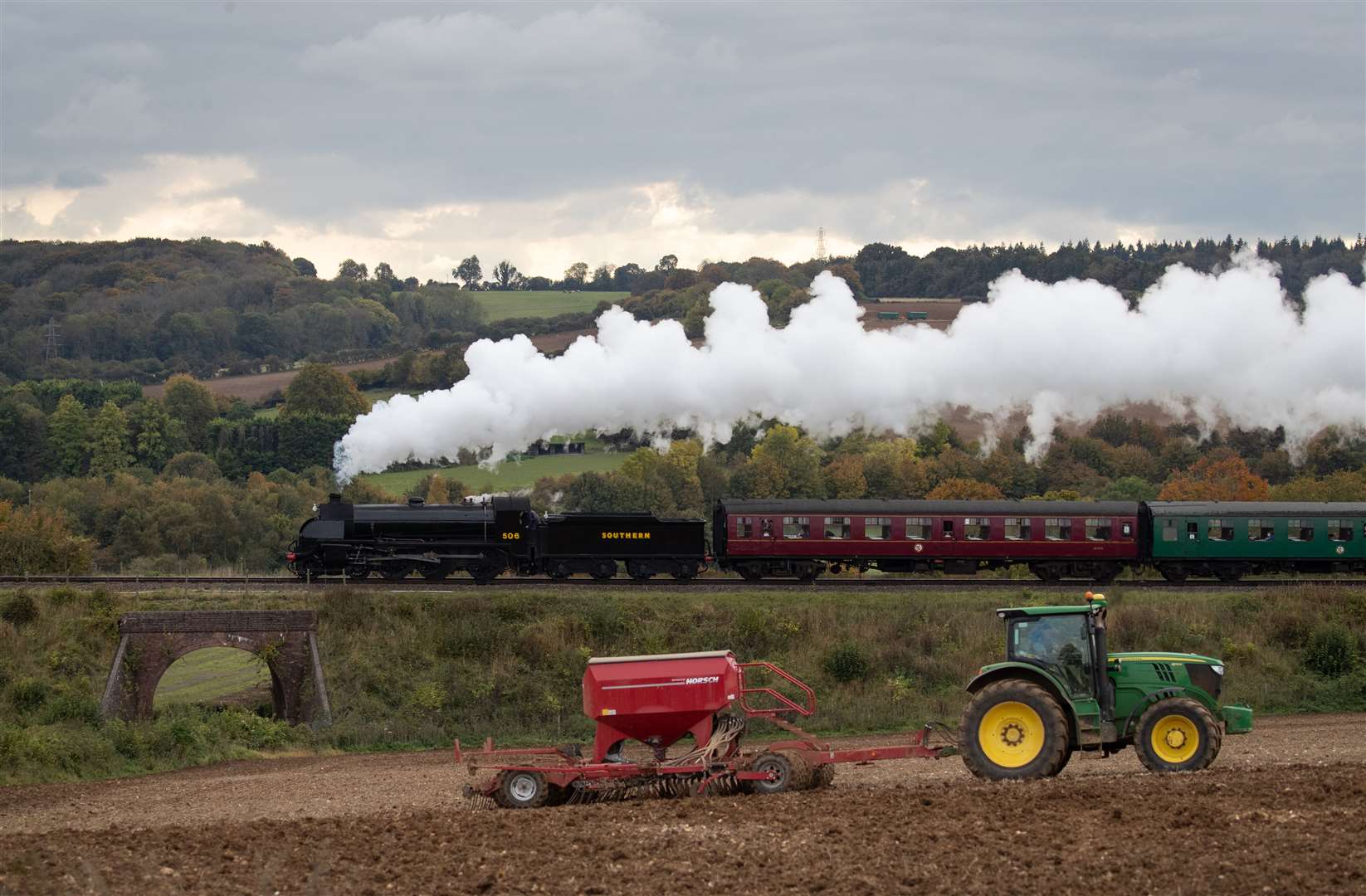 The S15 class steam locomotive 506 passes a tractor in a field as it makes its way along the Mid Hants Railway, near to Ropley in Hampshire, during the weekend’s Autumn Steam Gala (Andrew Matthews/PA)