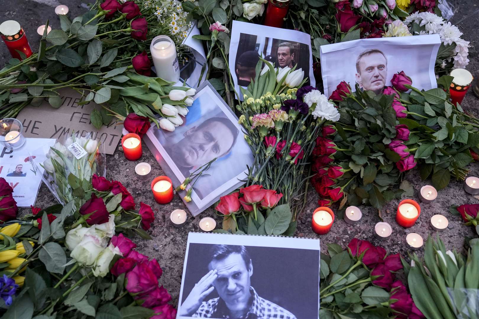 Portraits of Russian opposition leader Alexei Navalny, flowers and candles on the ground as people protest in front of the Russian embassy in Berlin, Germany (AP Photo/Ebrahim Noroozi)