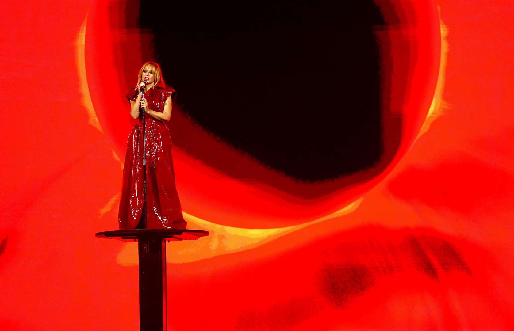 Kylie Minogue on a podium in a red leather-style ensemble (James Manning/PA)
