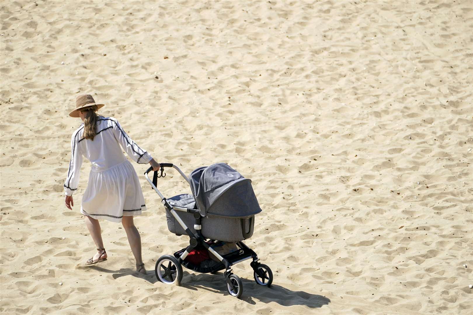 A woman pulls a pushchair across the beach in Bournemouth (Steve Parsons/PA)
