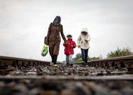 A Syrian mother and her daughters walks along the train tracks running from Serbia into Roszke, Hungary to reach a gathering point where refugees and migrants wait for a transit bus to pick them up and take them on the four hour journey north across Hunga