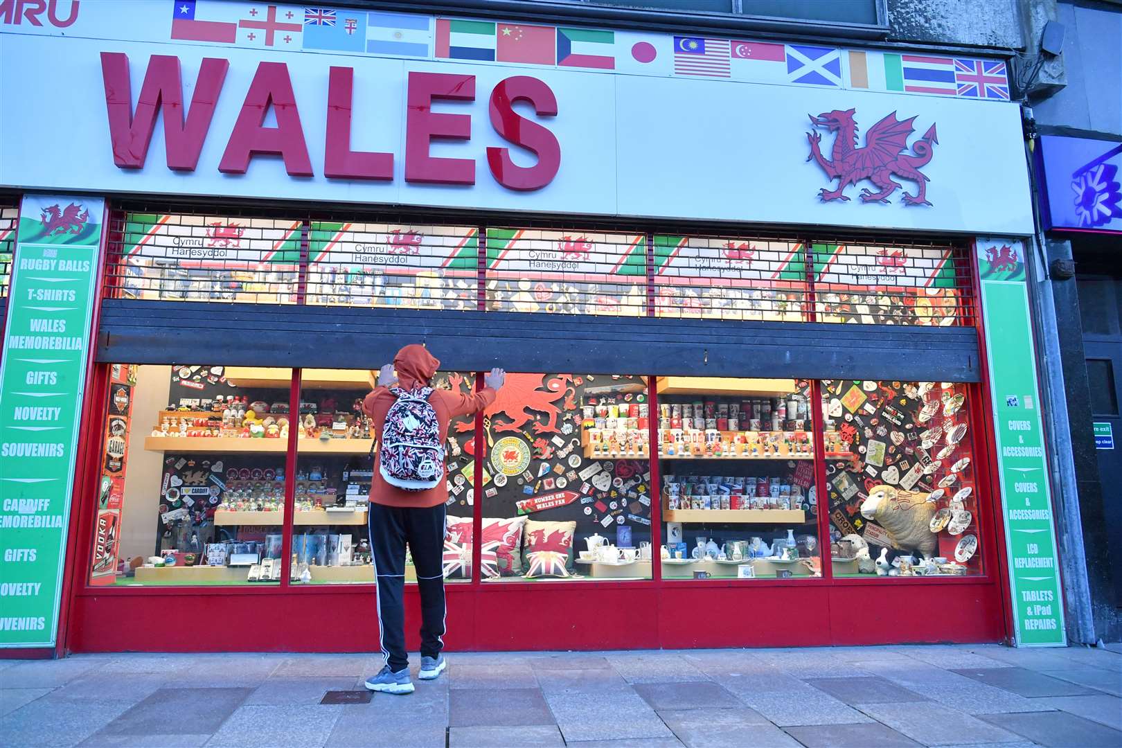 A shop owner pulls the shutters down on the Wales souvenir shop in Cardiff city centre before the ‘firebreak’ lockdown (Ben Birchall/PA)