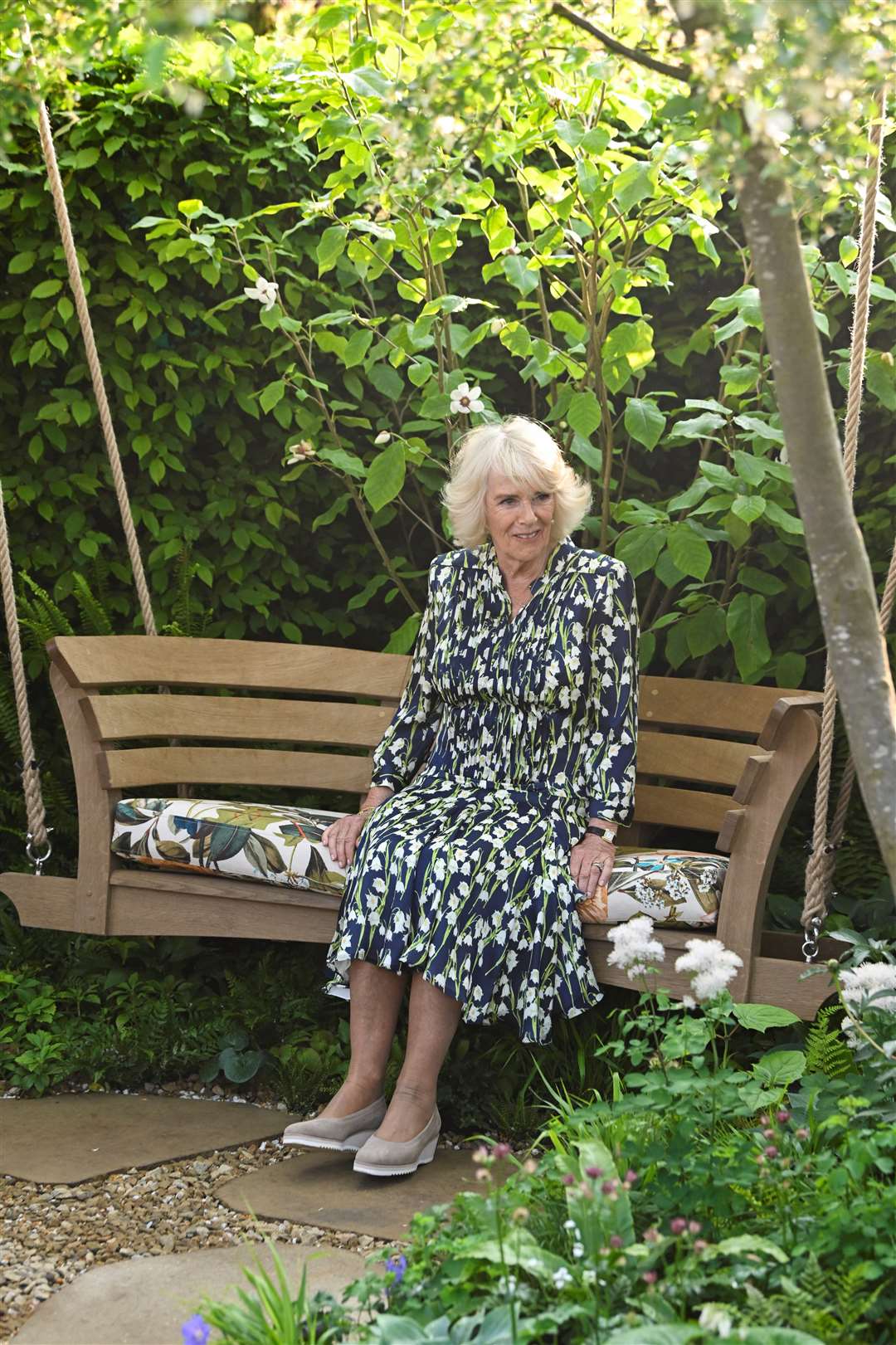 Camilla sits on a swing bench (Toby Melville/PA)