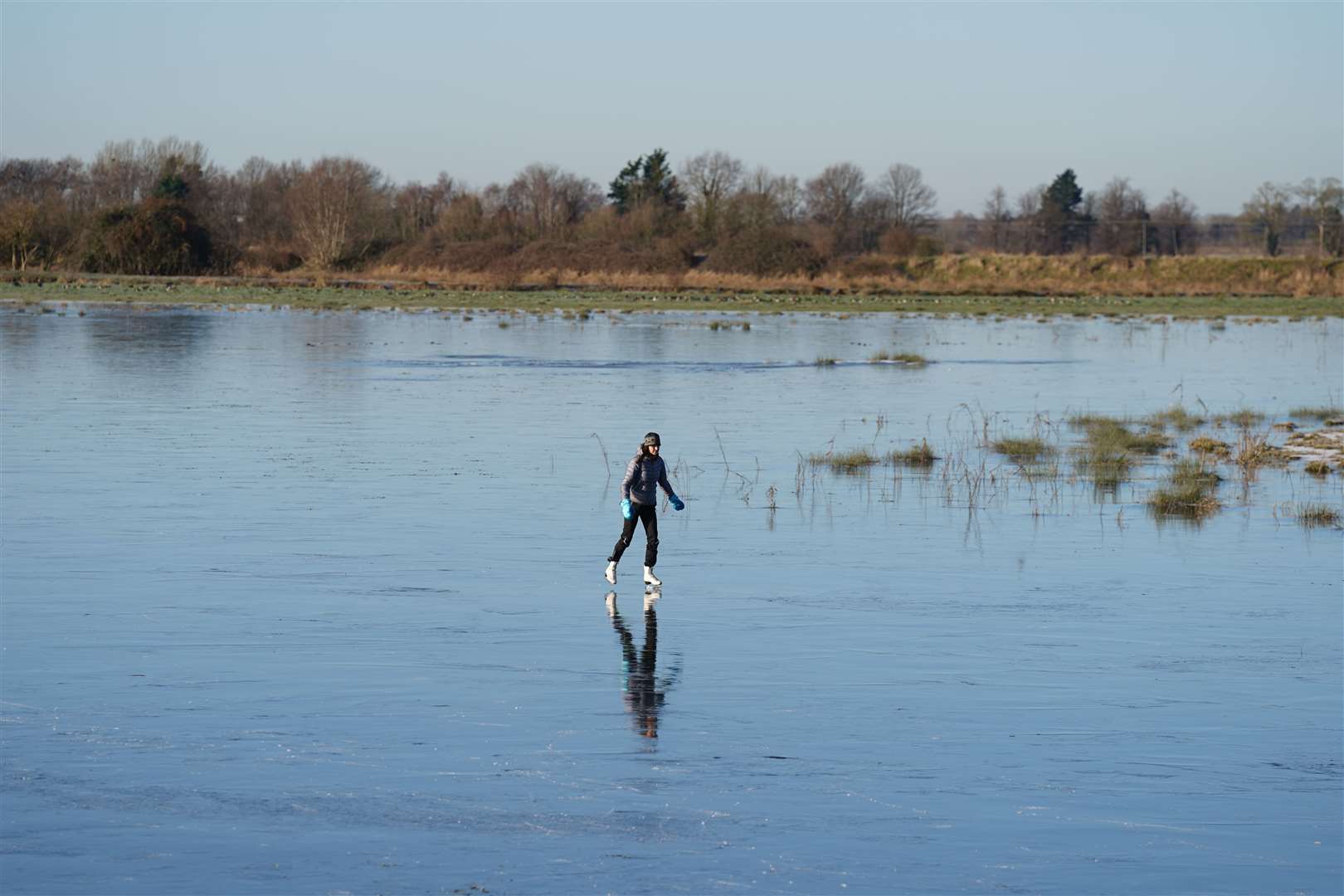 Fen skaters on a frozen flooded field in Upware, Cambridgeshire (Joe Giddens/PA)