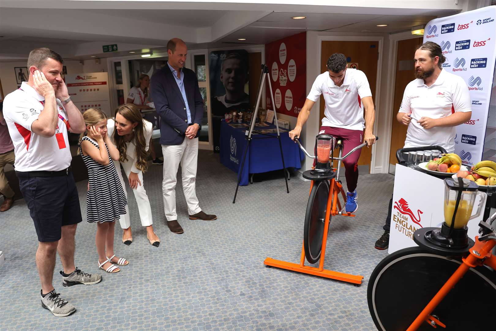 Tim Lawler and the Cambridges watch a demonstration of a bicycle-powered smoothie maker (Chris Jackson/PA)