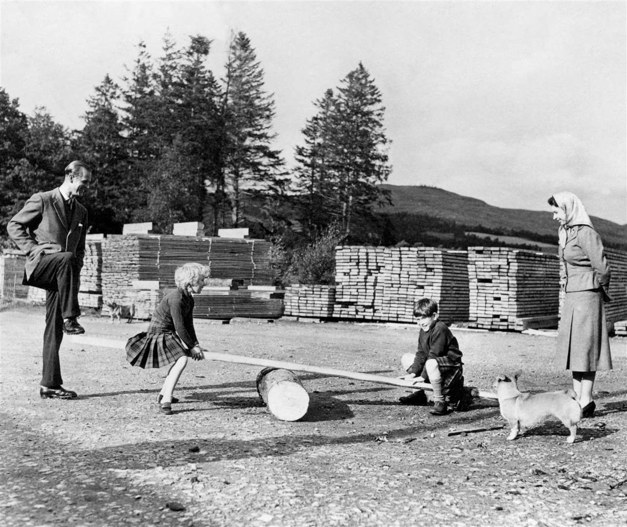 Charles and his sister Princess Anne, watched by their parents Elizabeth II and the Duke of Edinburgh, play on a see-saw at Balmoral in 1957 (PA)