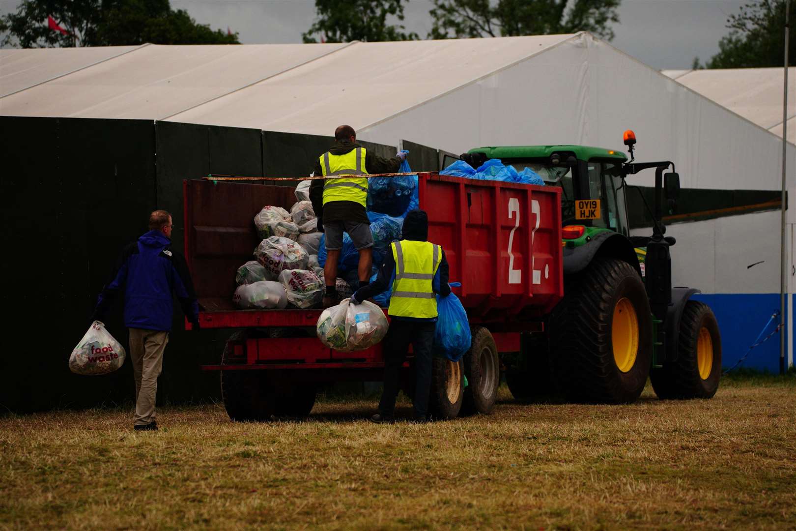 Workers load waste bags on a trailer pulled by a tractor (Ben Birchall/PA)